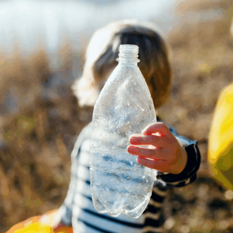 Child holding up a plastic bottle from picking up plastic pollution