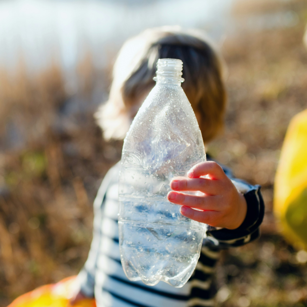 Child holding up a plastic bottle from picking up plastic pollution