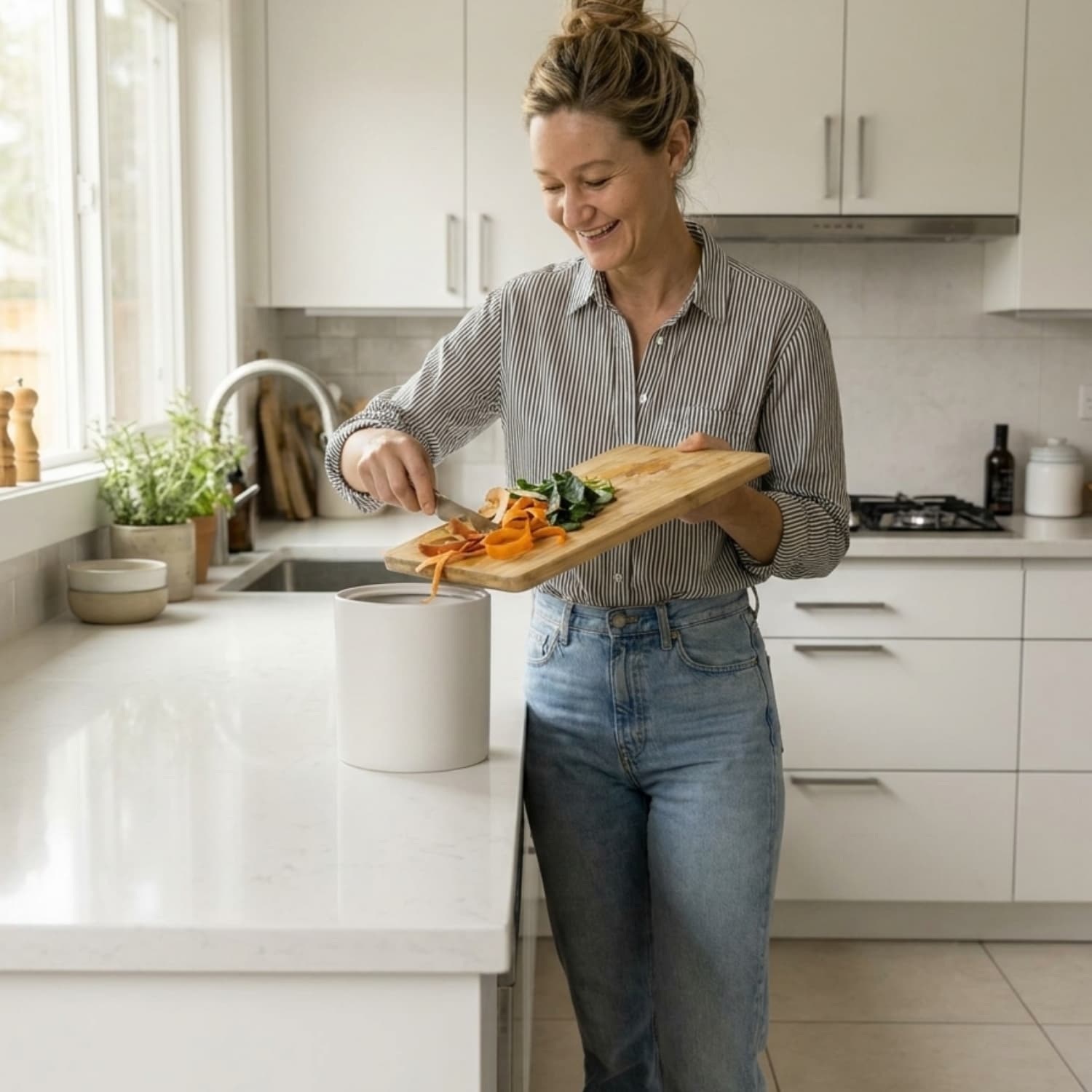 Woman her in her kitchen putting food scraps into a compost bucket.