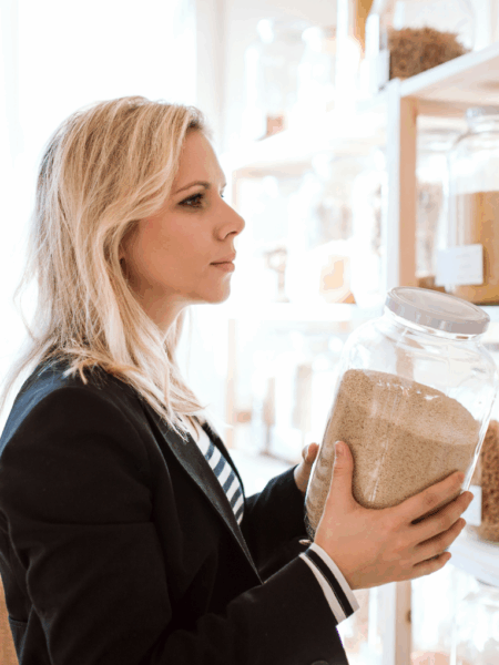 a woman holding a jar of grains at a zero waste store