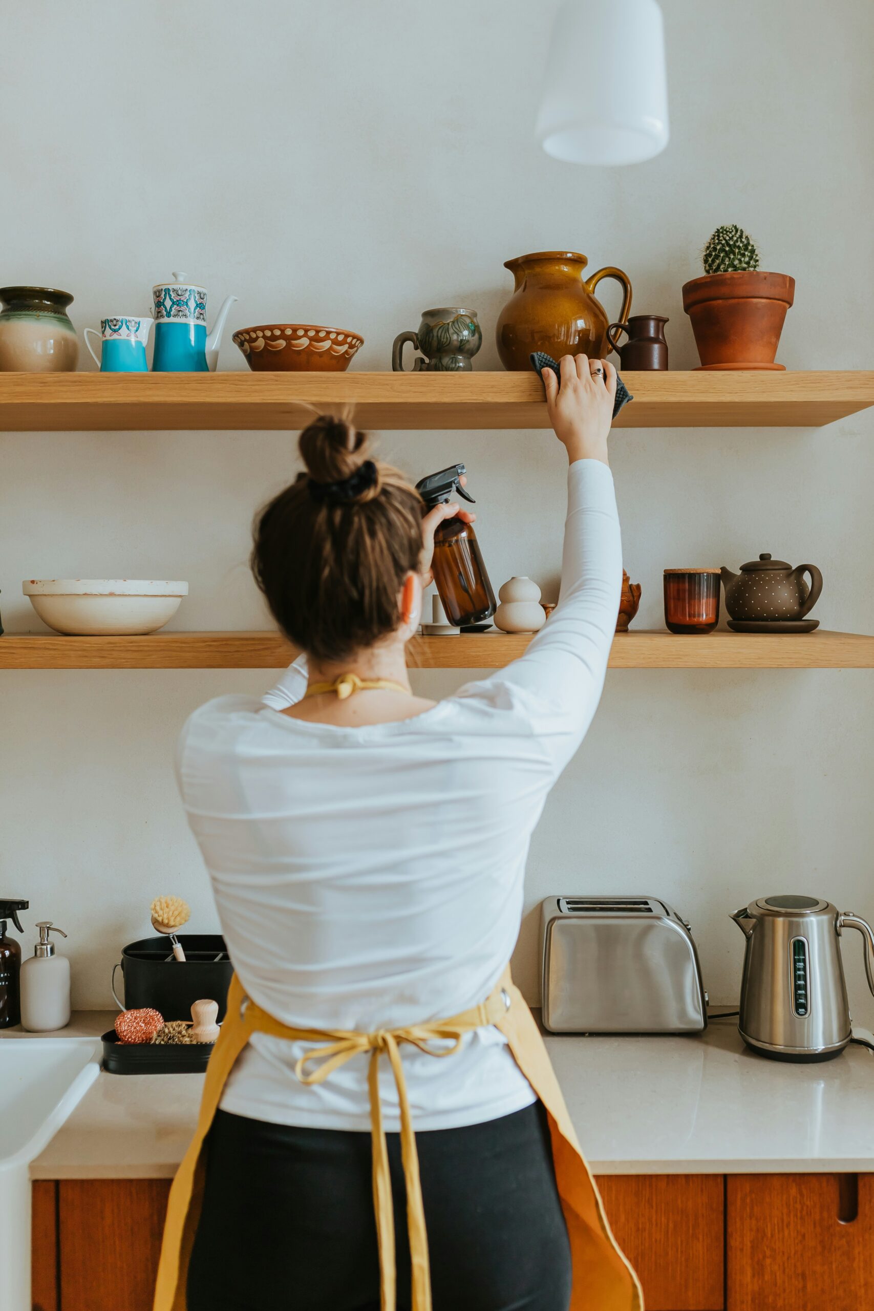 woman in kitchen cleaning a shelf