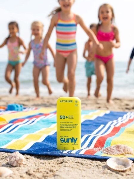Non Toxic Sunscreen Attitude Kids image of sunblock on a beach blank on the sand and kids in the background running