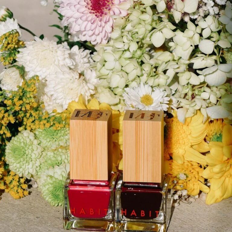 Non toxic nail polish Habit 2 bottles sitting next to each other in front of flowers