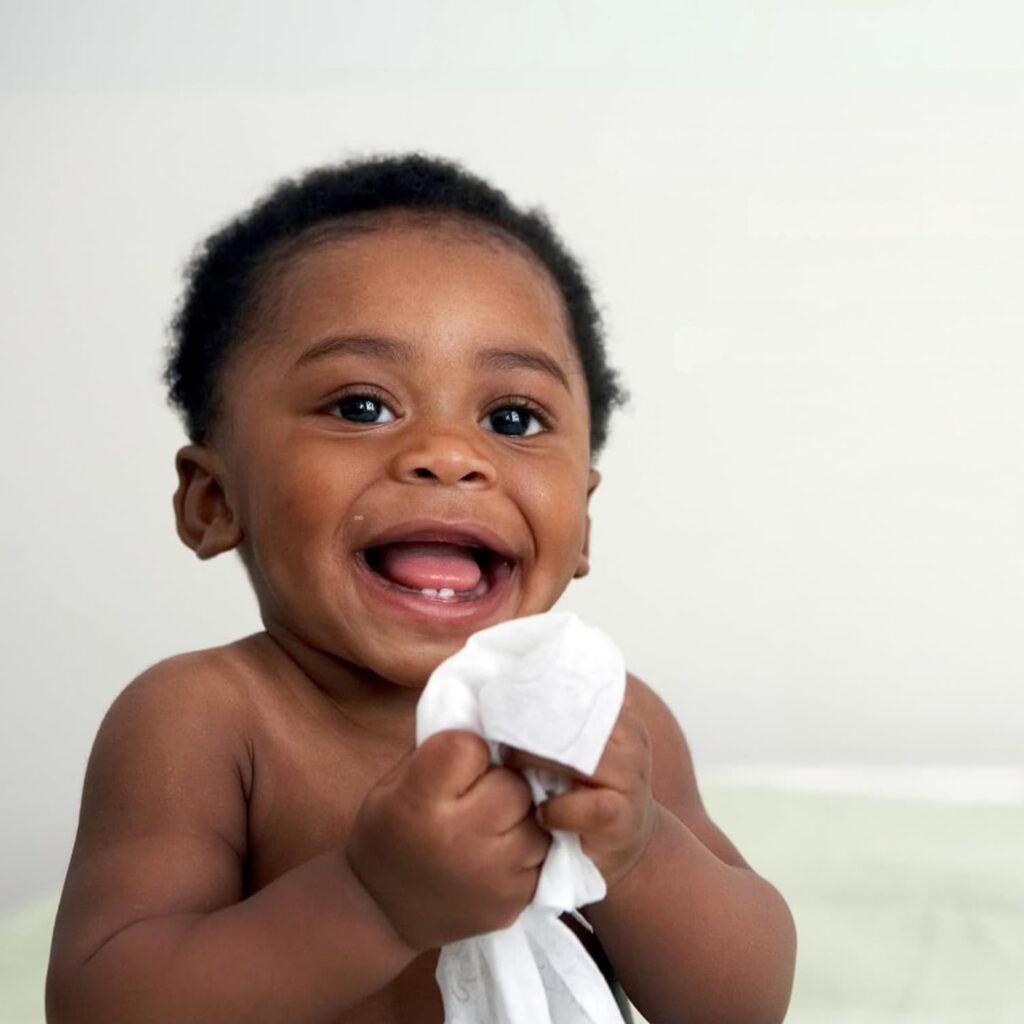baby smiling holding a non-toxic wet wipe