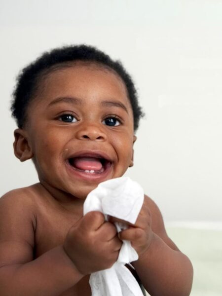 baby smiling holding a non-toxic wet wipe