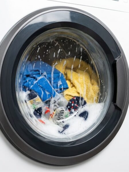 Washing machine washing clothes with soap.