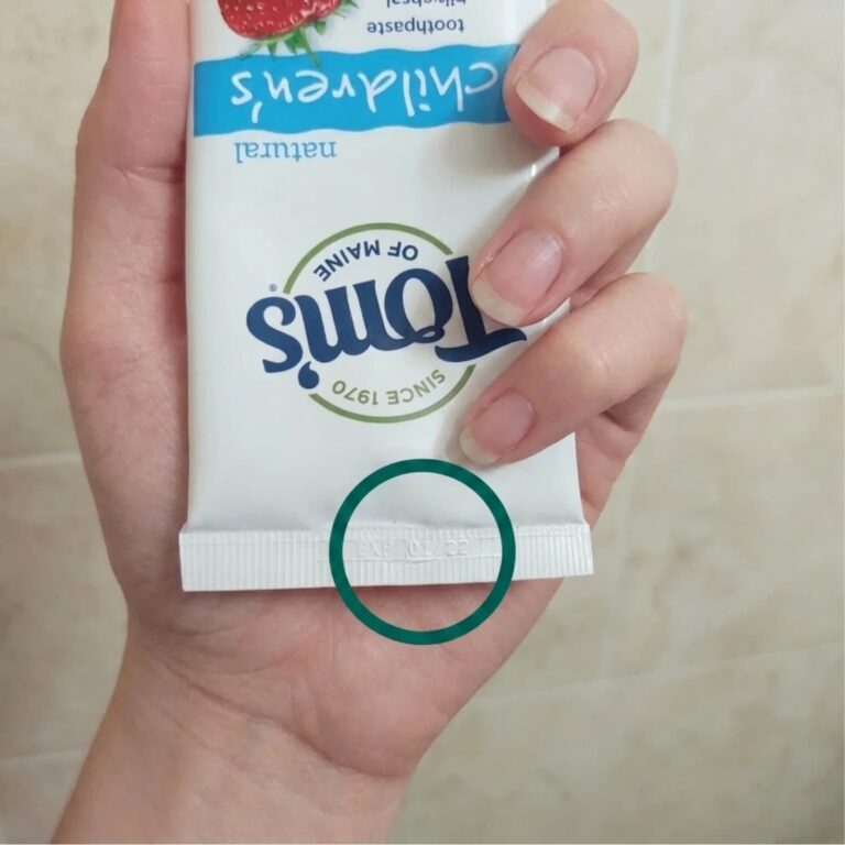 A woman holding a Tom's toothpaste in her hand, with the expiration date circled in green.