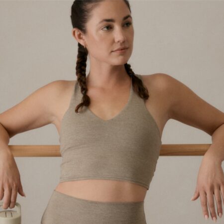 Woman leaning against the wall in athletic wear.