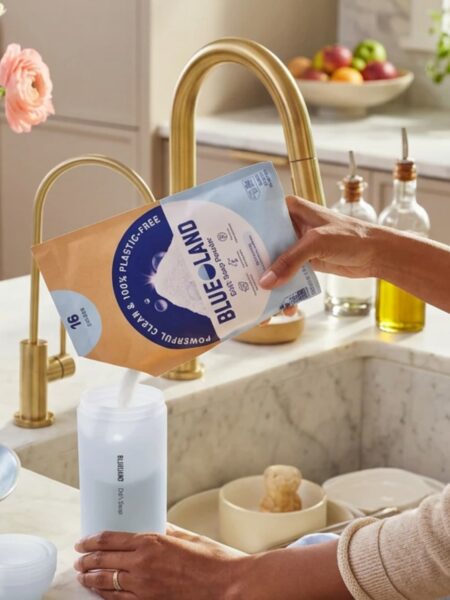Woman pouring Blueland dishwashing powder into the forever bottle.
