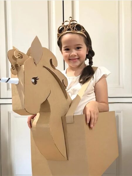 Girl dressed in DIY halloween costume that is a cardboard unicorn.