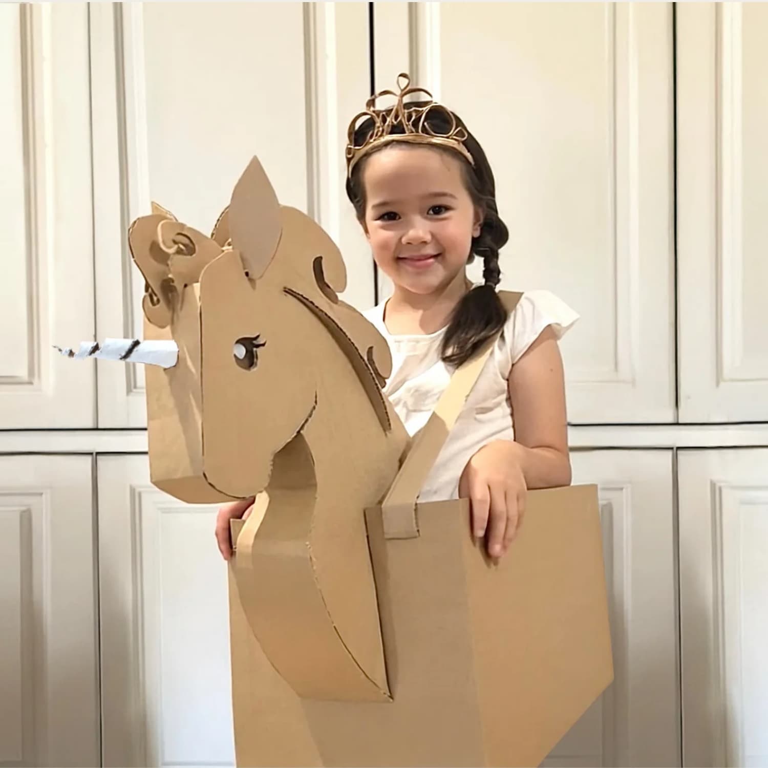 Girl dressed in DIY halloween costume that is a cardboard unicorn.