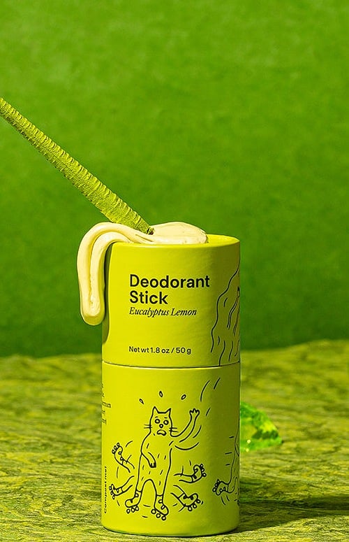 Meow Meow Tweet Eucalyptus Lemon deodorant stick in a compostable paper tube on a green set