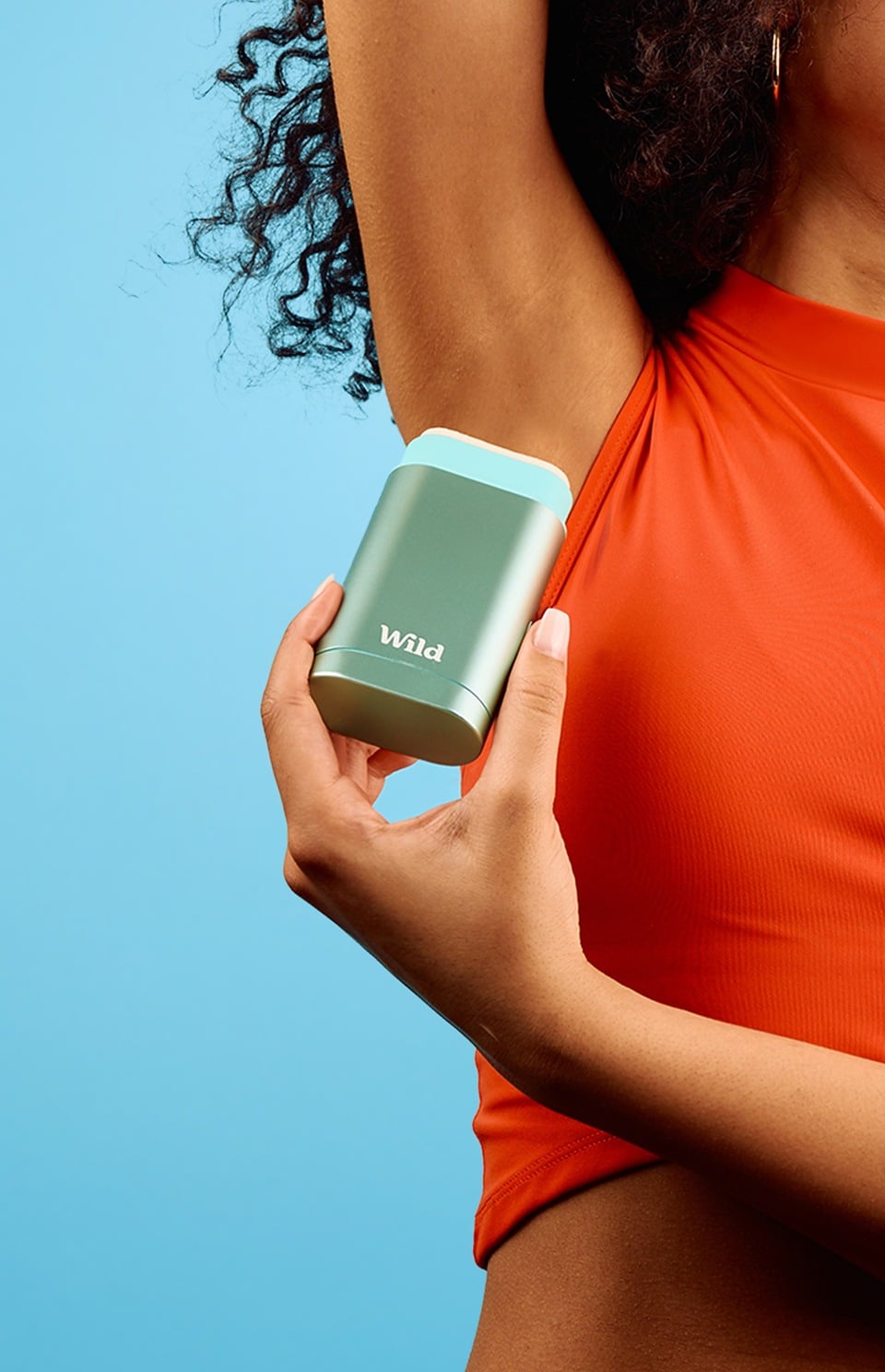 Woman holding a Wild refillable aluminum deodorant case against a blue sky